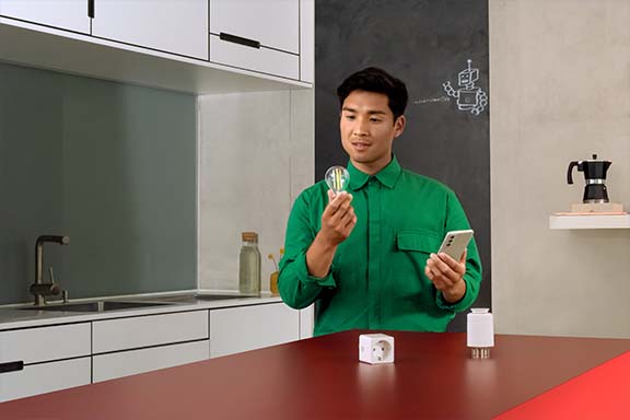 Person mit Smarthome-Steckdose, -Lampe und -Thermostat